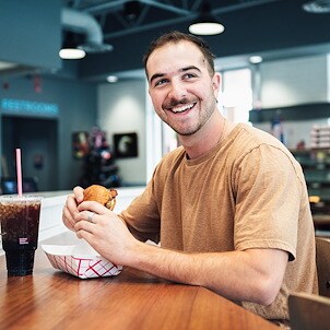 Man enjoying hamburger and fountain drink at UDF