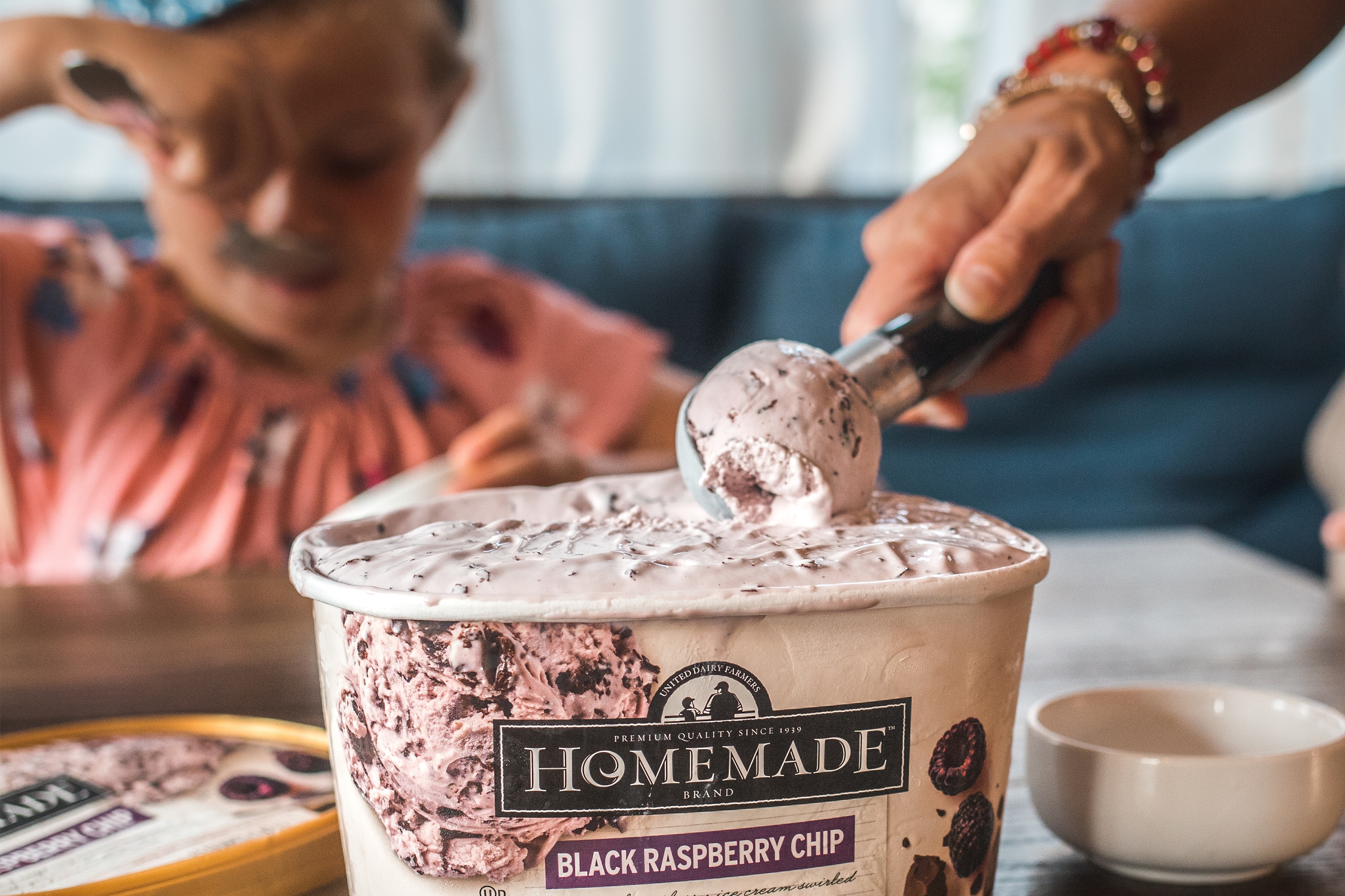 Mother scooping Homemade Brand Black Raspberry Chip Ice Cream for child