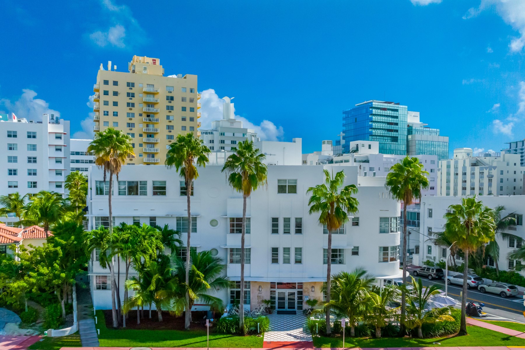 A white building with palm trees in front of it and a blue sky.