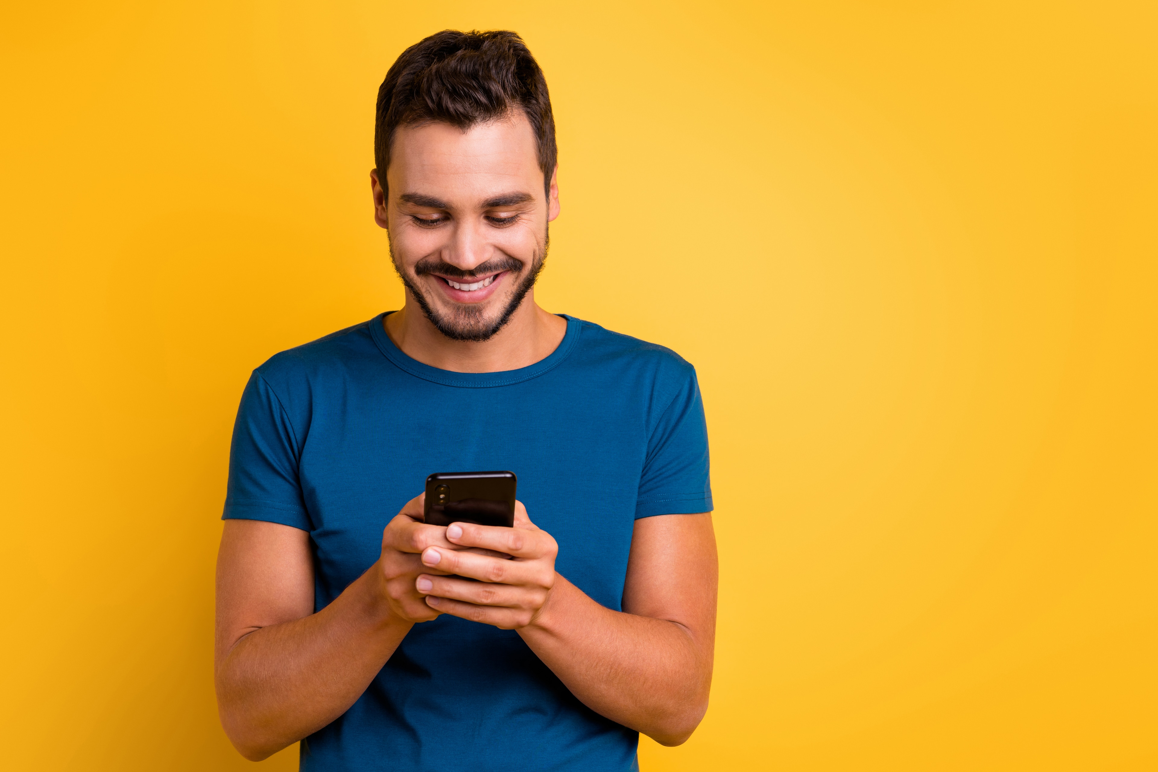 Air Academy Credit Union SEG perks image showing a smiling man using his smartphone against a yellow background