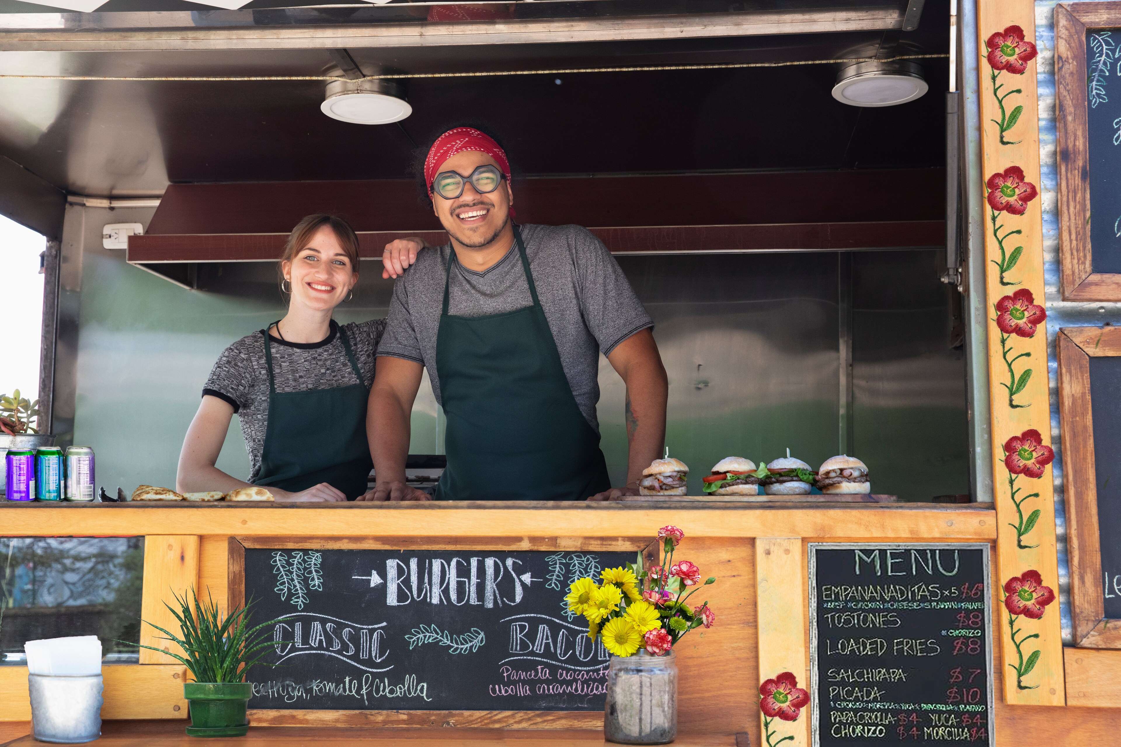 Cheerful Small Business Owners Posing Inside Food Truck Window