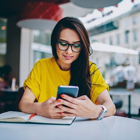 Professional Woman In Glasses Checking Smartphone At Outdoor Cafe Table