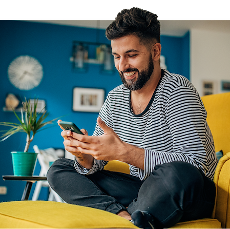 Young Man Sitting In Armchair Smiling While Using Digital Tablet