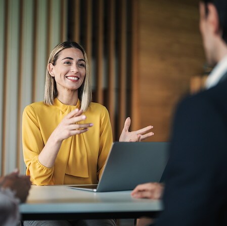 Smiling Professional Speaking In Meeting With Laptop On Table