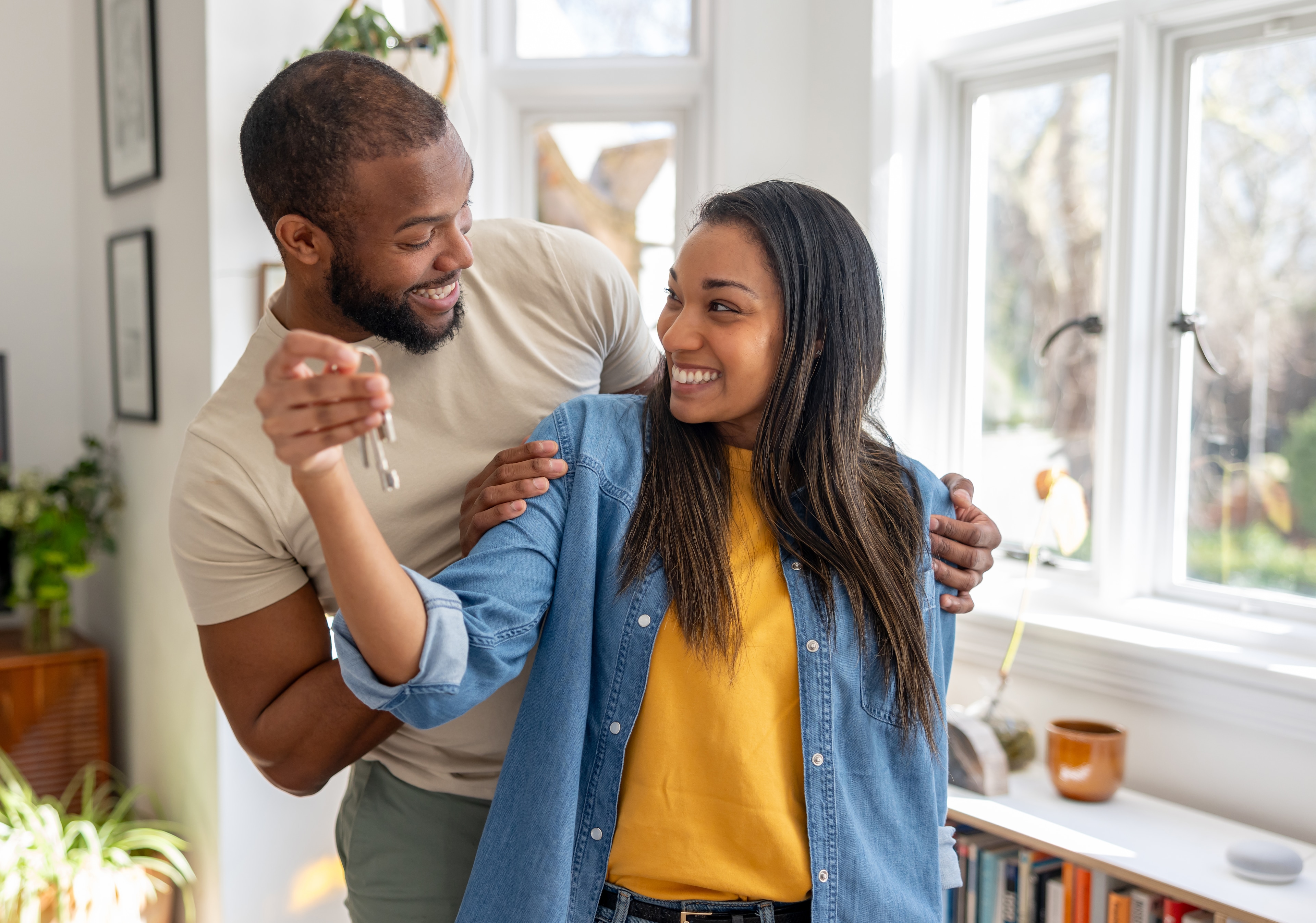 Happy couple embracing in their home while holding up the keys to their new house