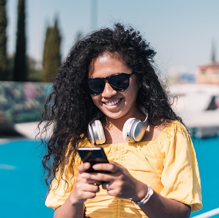 Smiling Woman With Sunglasses Using Smartphone Outdoors