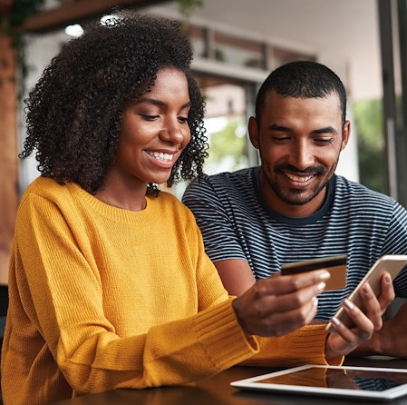 Happy Couple Entering Credit Card Details On Smartphone Together