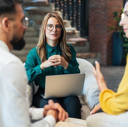 Financial advisor listening to clients during a consultation with a laptop open