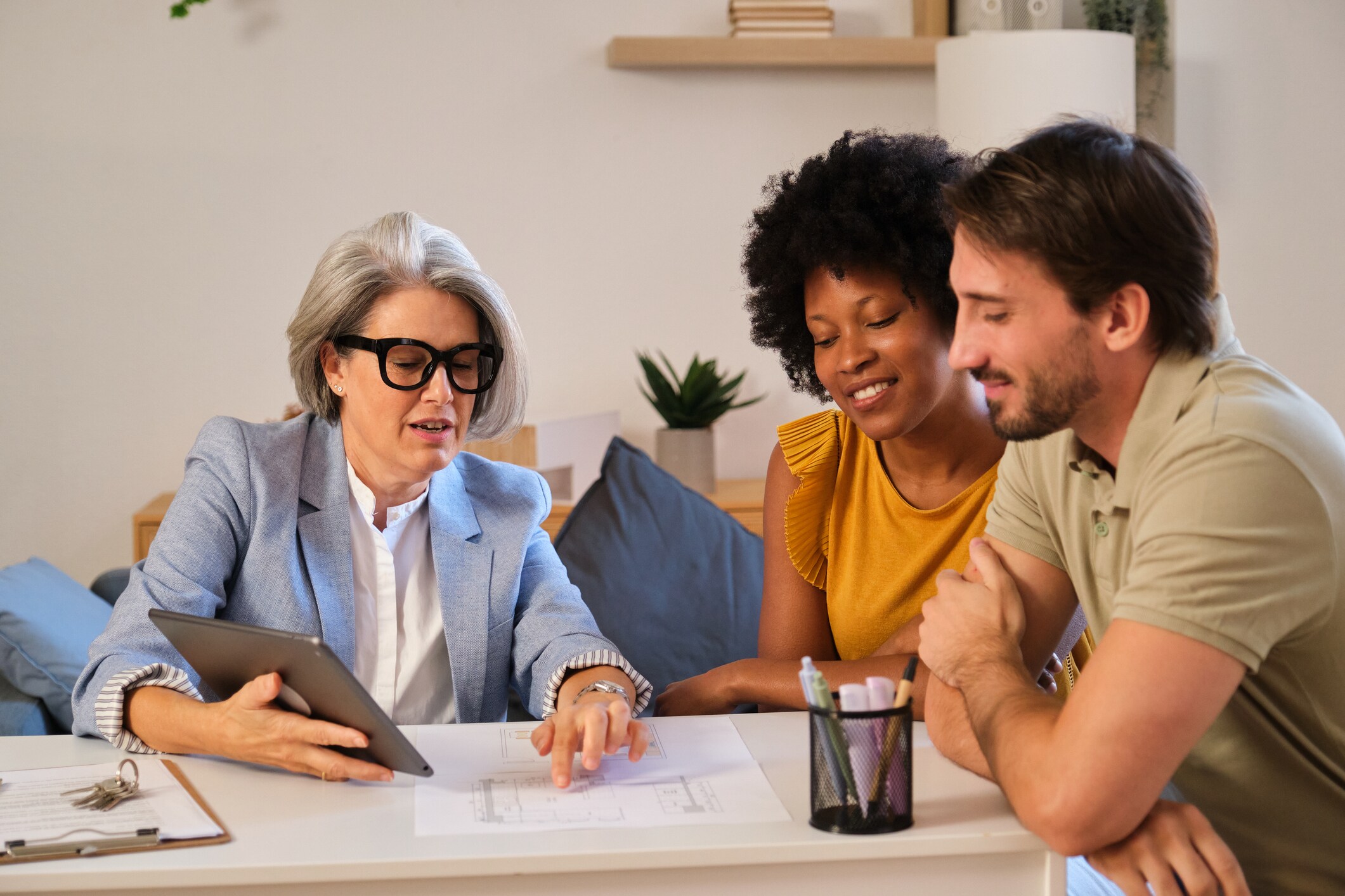Professional consultant pointing at blueprints with a couple