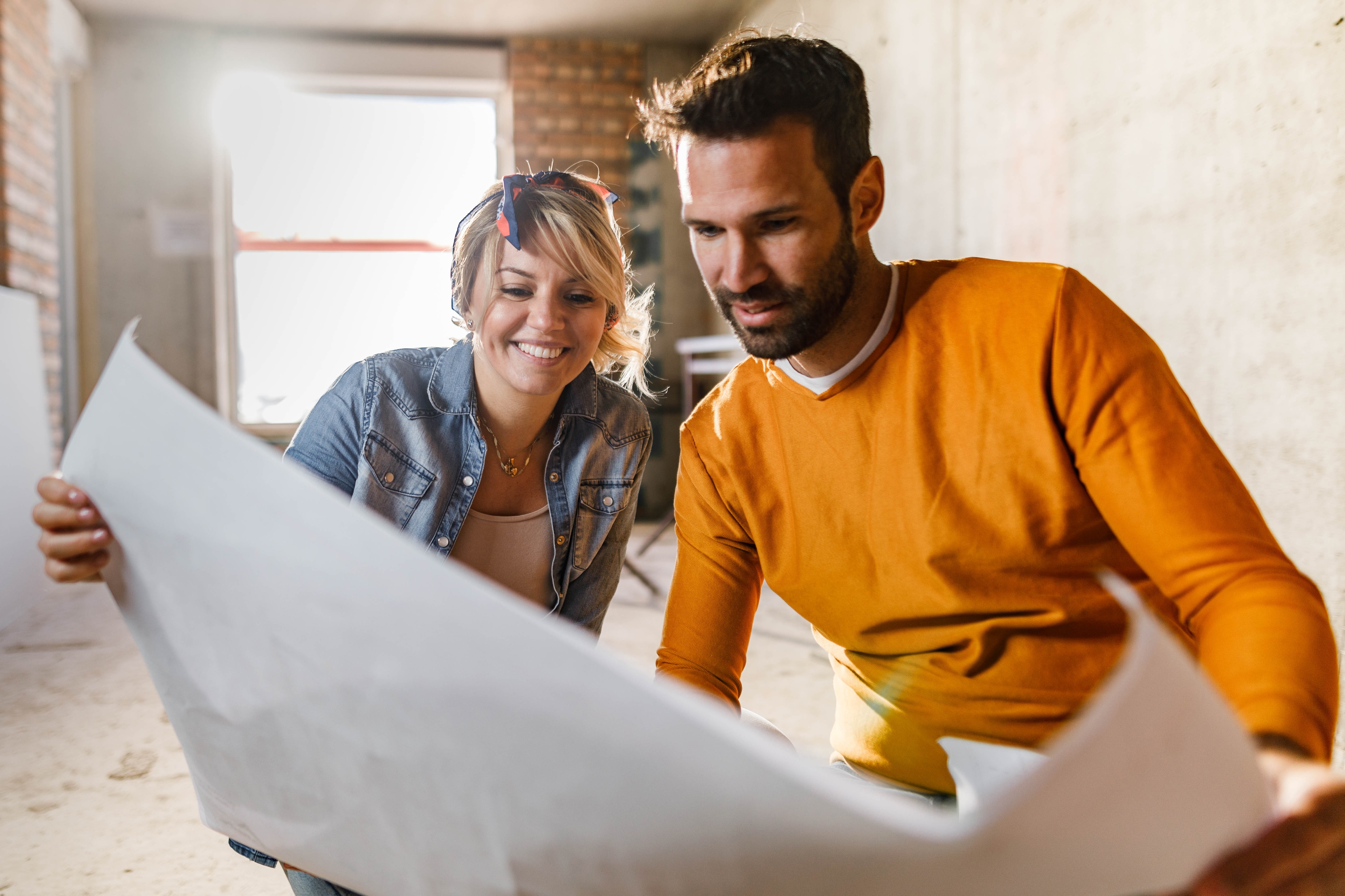 Couple looking at architectural blueprints together while renovating a house