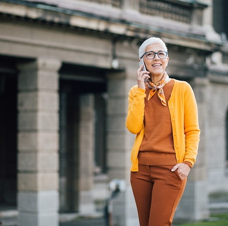 Women in yellow sweater on her phone in front of a building