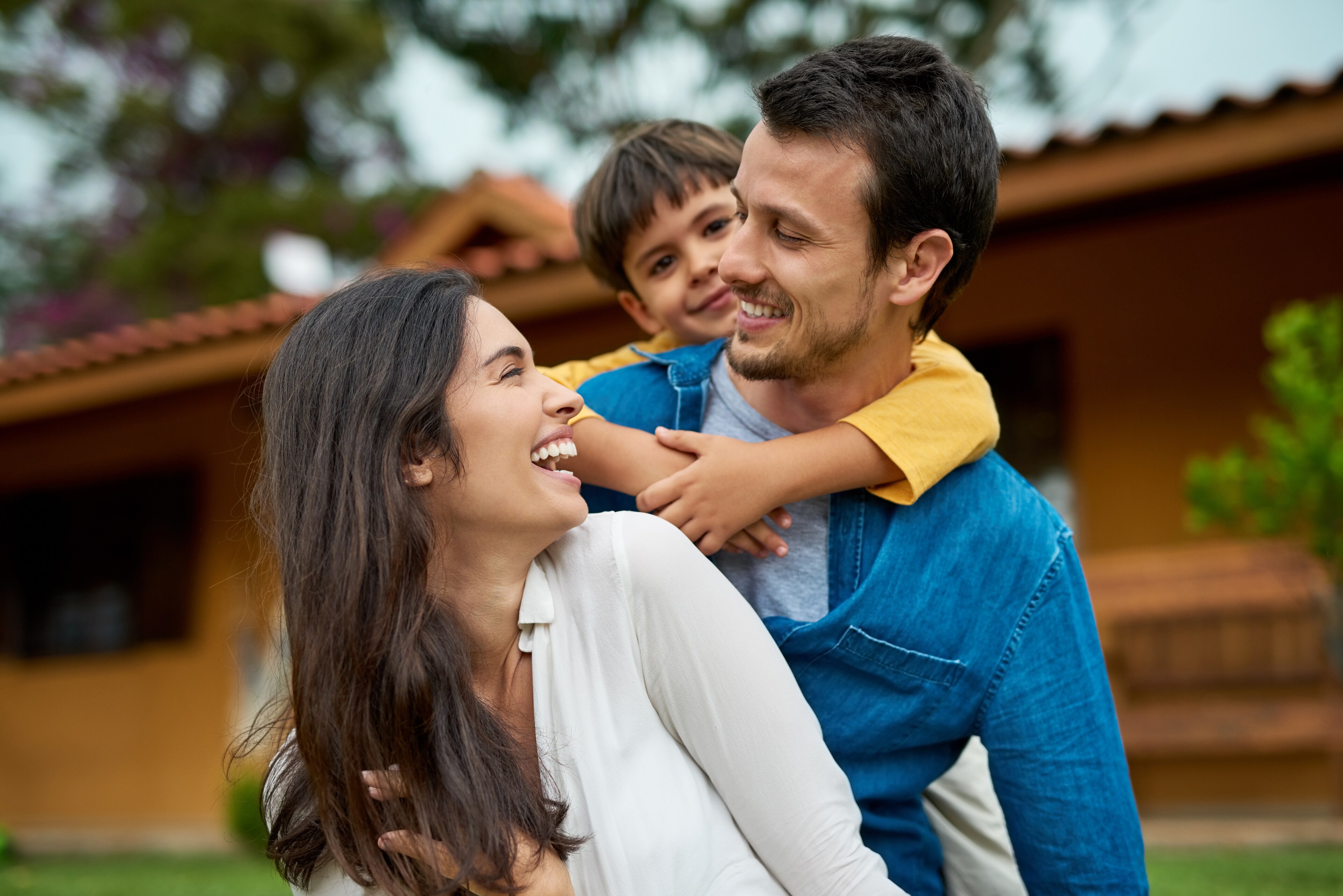 Smiling Family Playing Outdoors With Son On Parents Back