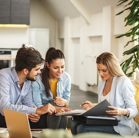 Couple reviewing documents with a financial advisor in a living room