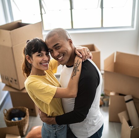 Happy young couple hugging surrounded by boxes
