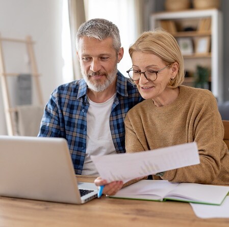 Senior Couple Reviewing Financial Papers And Laptop Together At Desk