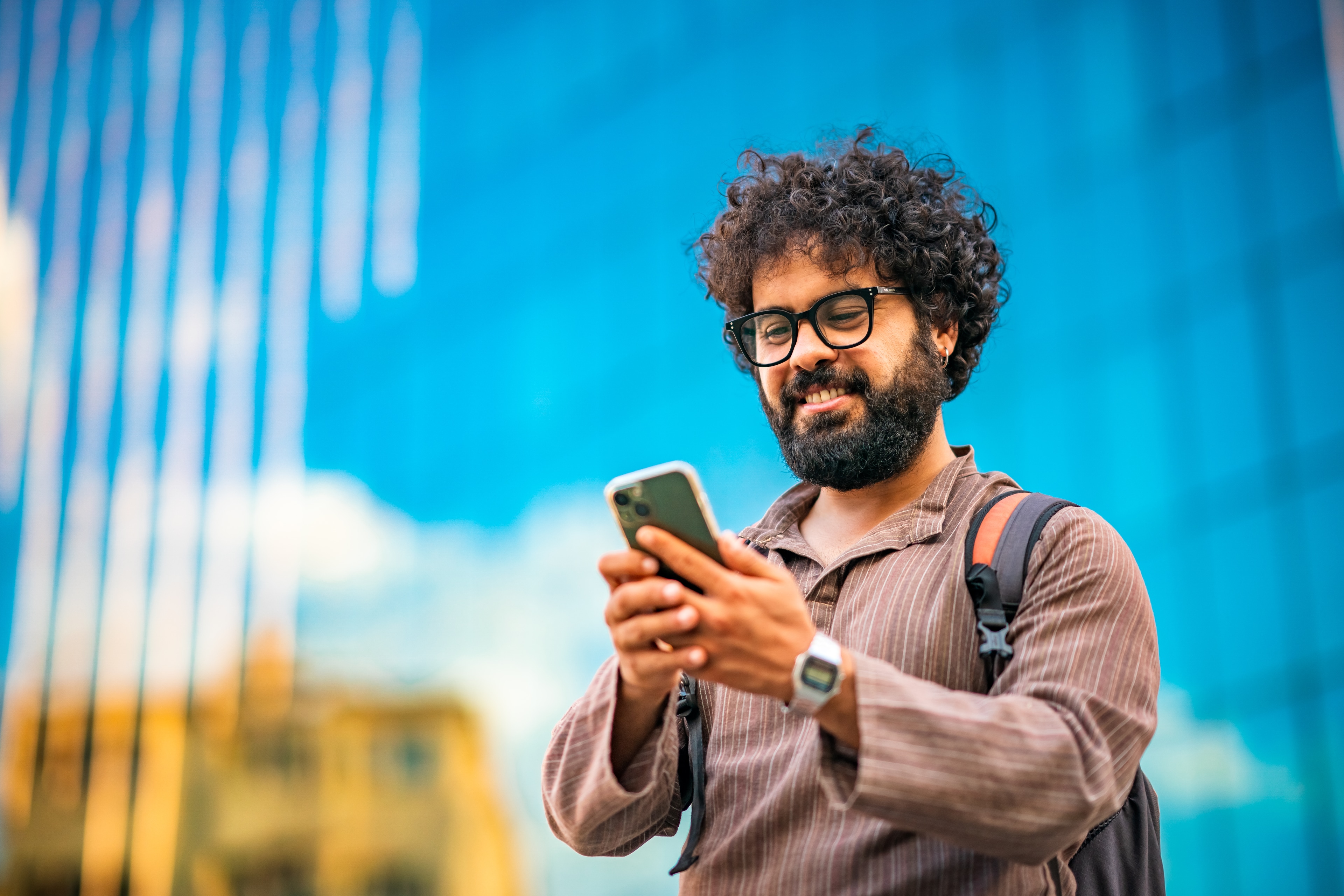 Smiling bearded man with glasses using his smartphone at Colorado