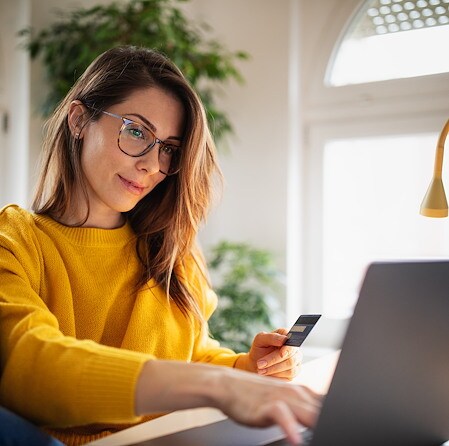 Woman using credit card and laptop for online shopping at home
