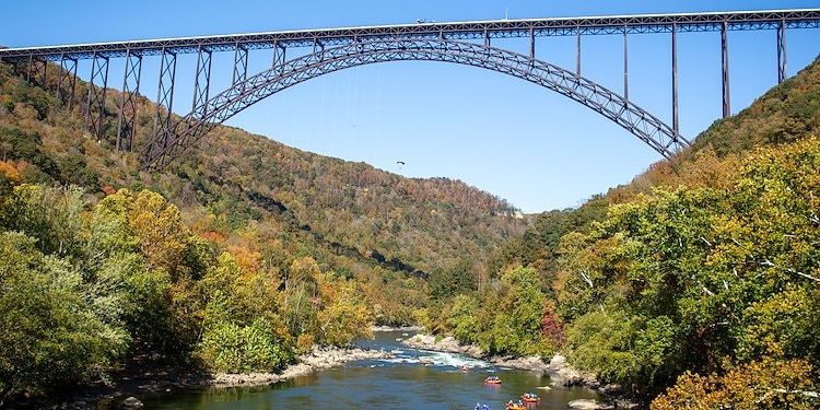 Rafters going under the New River Gorge Bridge as basejumpers parachute down