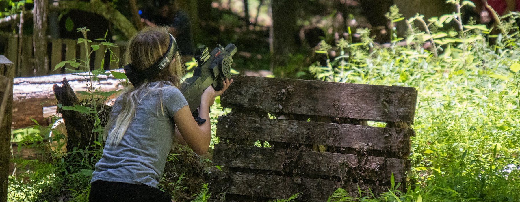A person crouches behind a wooden barrier during an intense paintball Adventures on the Gorge - Lansing West Virginia USA