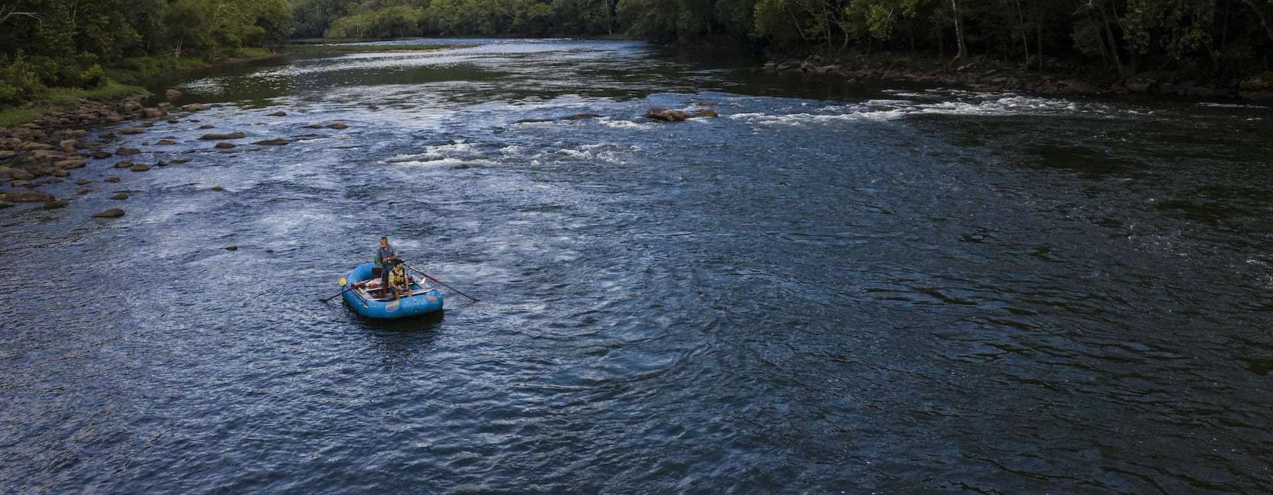 A serene river scene with two people in a blue raft Adventures on the Gorge - Lansing West Virginia USA