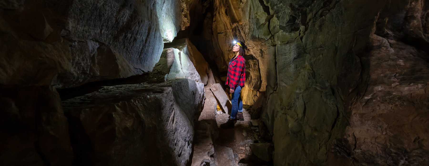 Adventures on the Gorge Lansing West Virginia USA - Headlamp stands in a narrow dimly lit cave passage