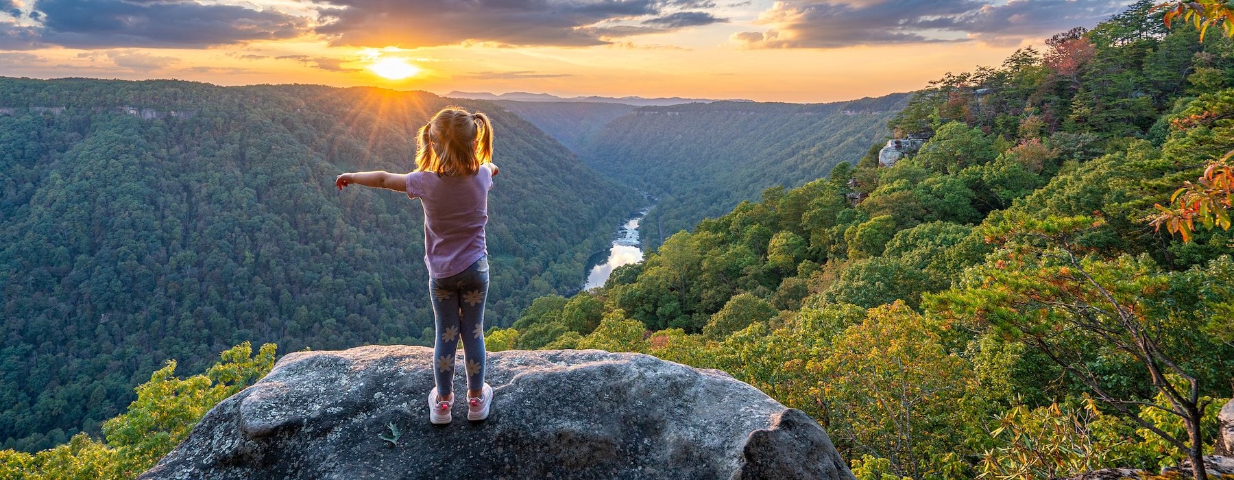 Adventures on the Gorge Lansing West Virginia USA - young girl stands on a cliff arms outstretched