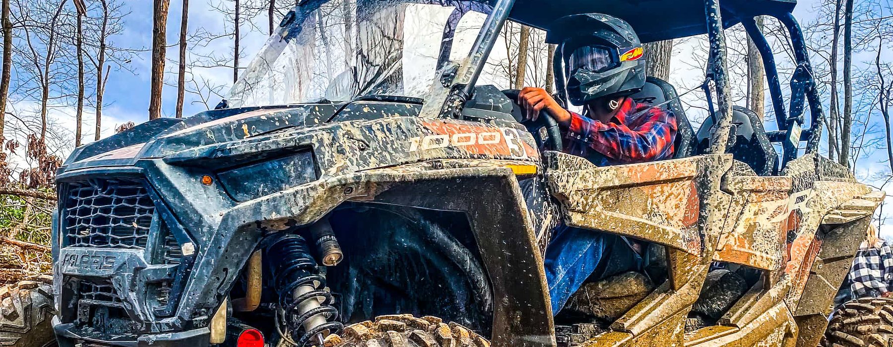 ATV driver in plaid jacket navigates through muddy forest trail Adventures on the Gorge - Lansing West Virginia USA