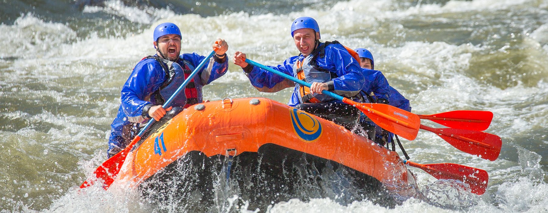 Group of people are whitewater rafting in a bright orange raft Adventures on the Gorge - Lansing West Virginia USA