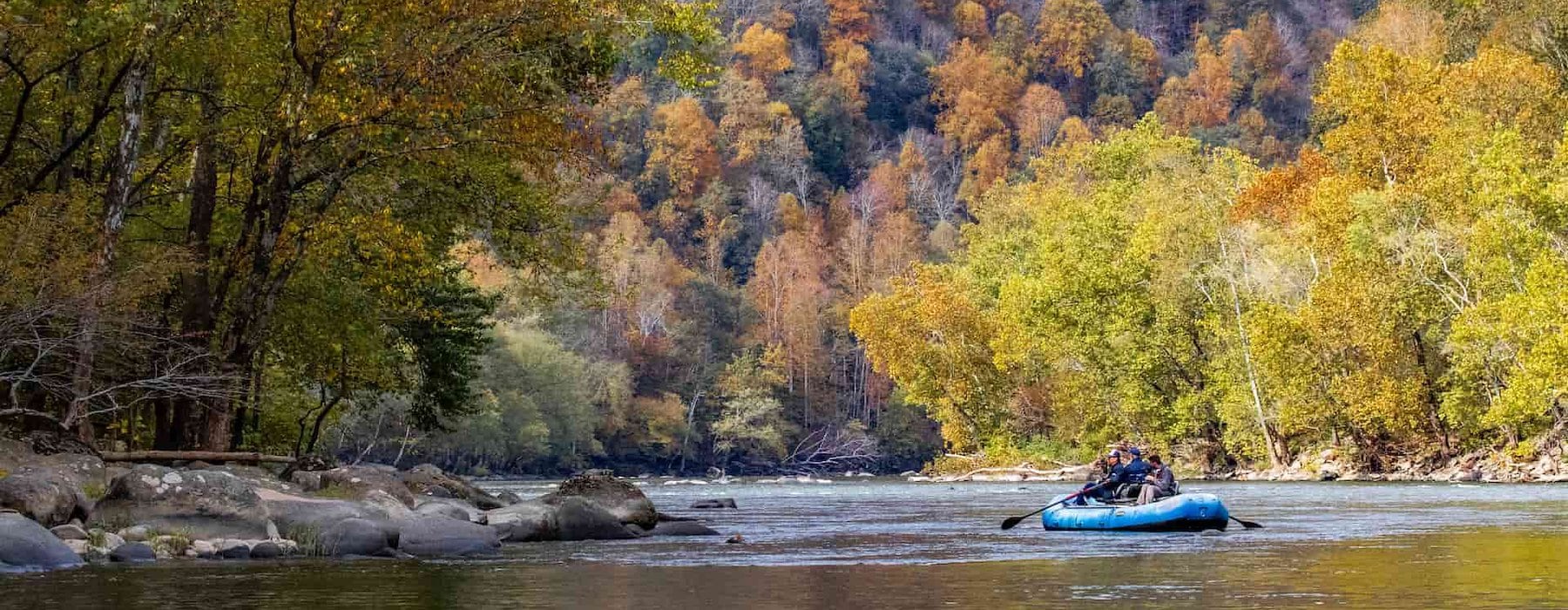 Group rafts on a calm river surrounded by vibrant autumn trees Adventures on the Gorge - Lansing West Virginia USA
