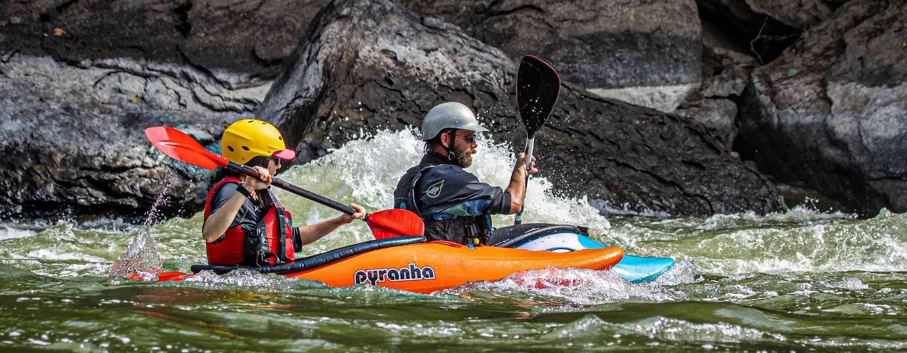 Life vests kayak through turbulent river rapids by rocky cliffs Adventures on the Gorge - Lansing West Virginia USA