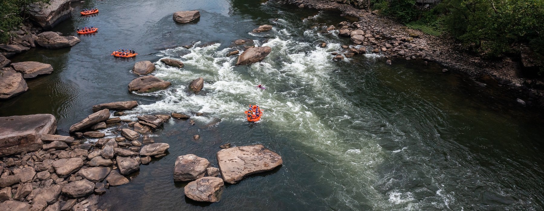 Rafting adventure on a river with multiple orange rafts navigating Adventures on the Gorge - Lansing West Virginia USA