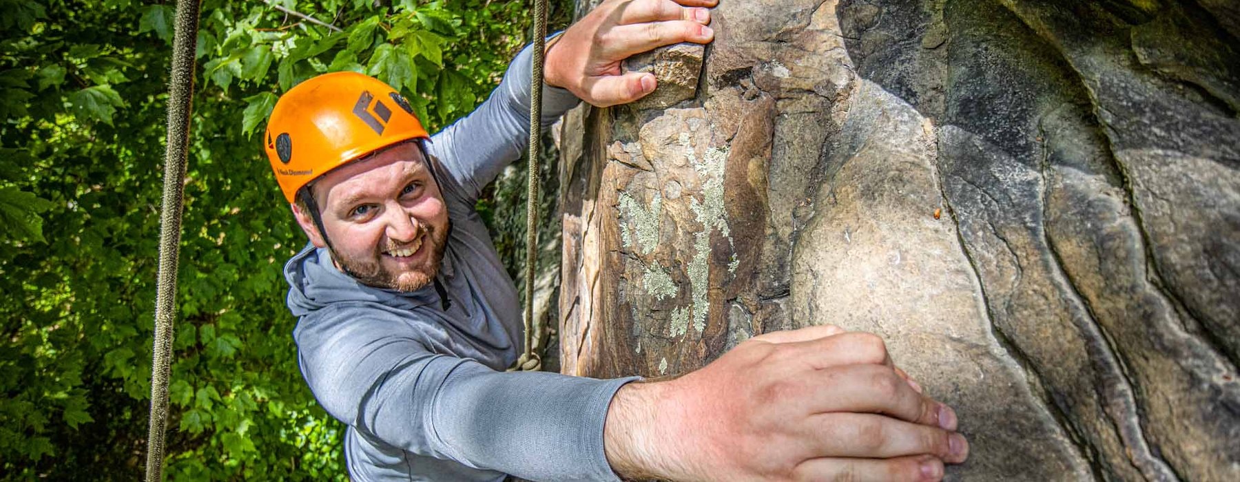 Smiling man climbs a rock face Adventures on the Gorge - Lansing West Virginia USA