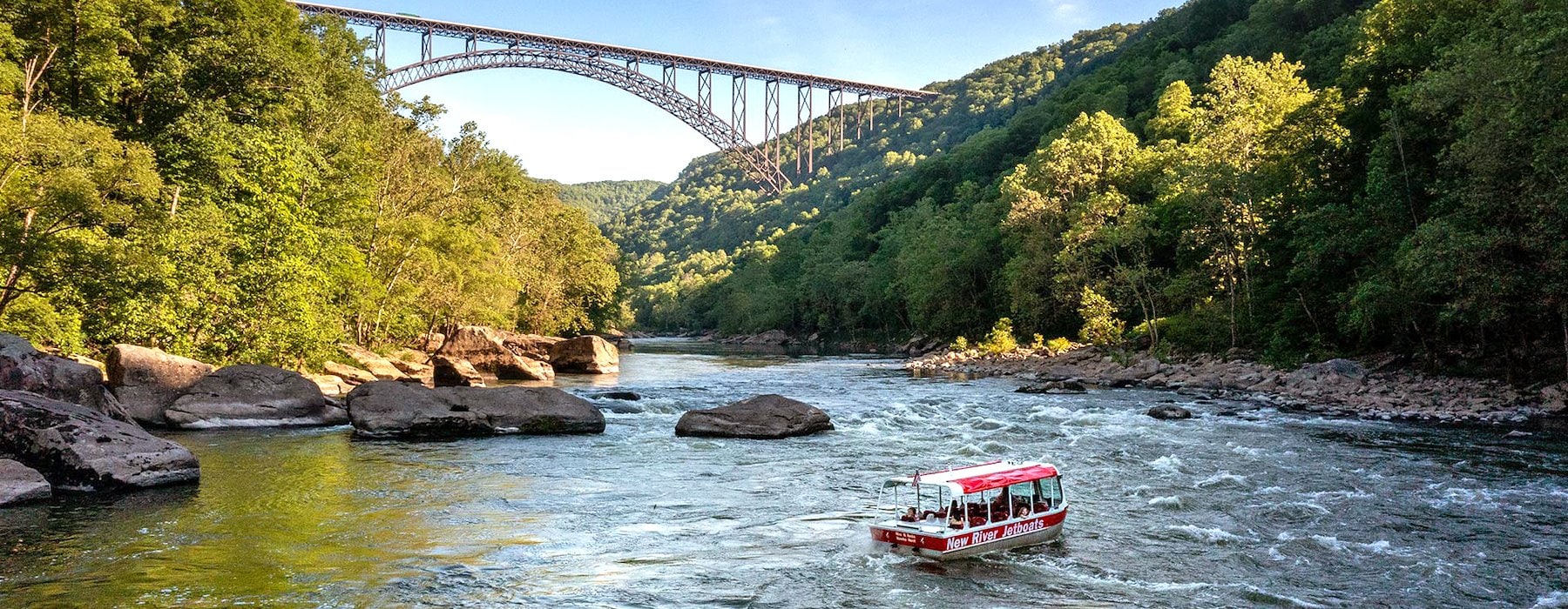 Tour boat navigates a calm river flanked by lush green hills Adventures on the Gorge - Lansing West Virginia USA
