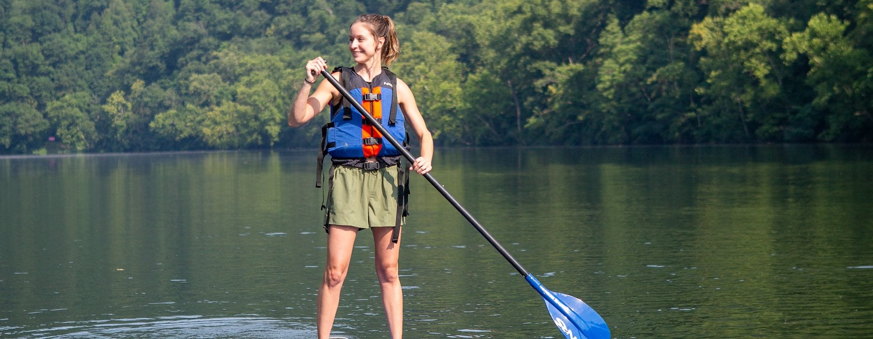 Woman balances on a paddle board in calm water Adventures on the Gorge - Lansing West Virginia USA