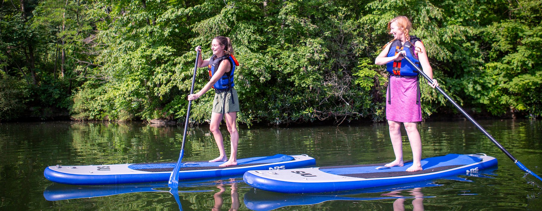 Women paddleboard on a serene lake surrounded Adventures on the Gorge - Lansing West Virginia USA