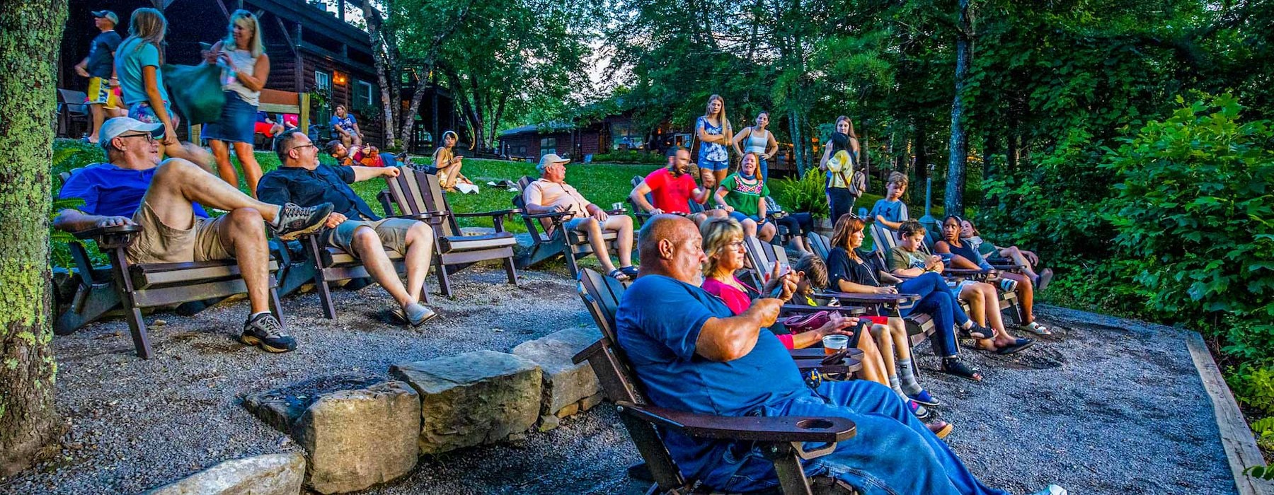 A group of people sits on Adirondack chairs in a wooded outdoor setting Adventures on the Gorge - Lansing West Virginia USA