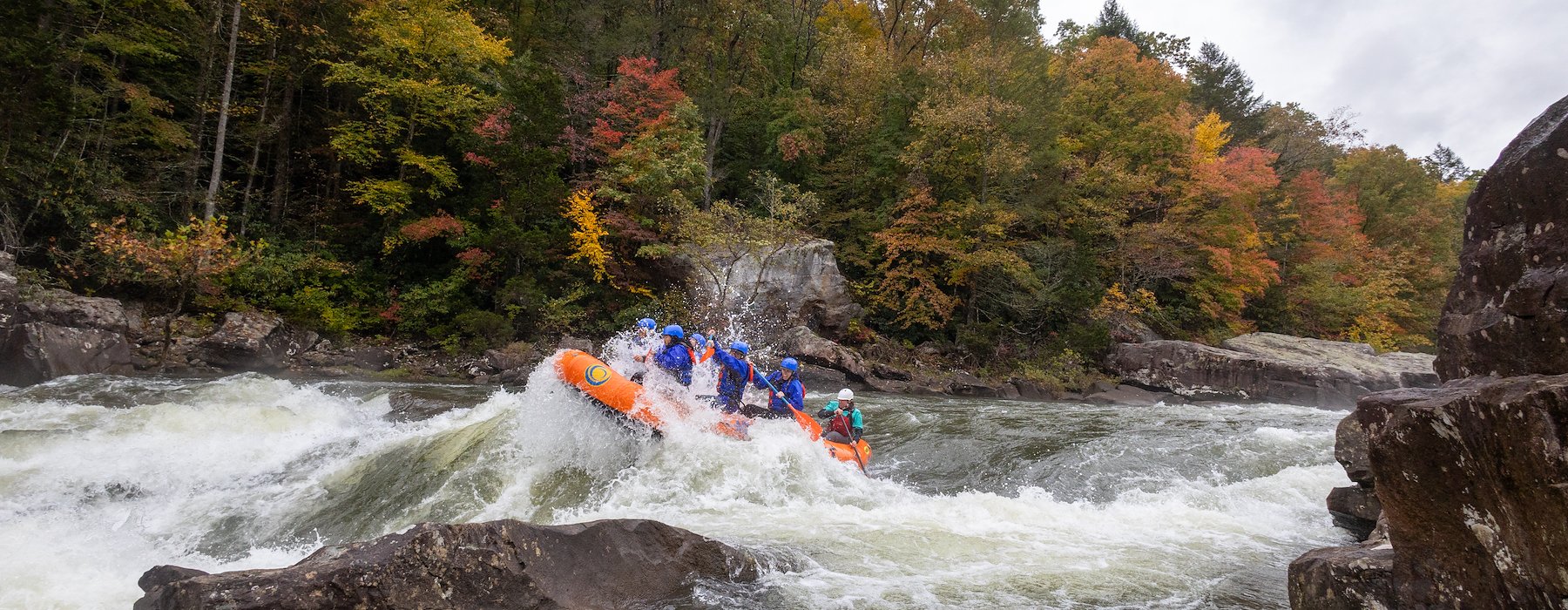 A group of people white water rafting in an orange inflatable raft Adventures on the Gorge - Lansing West Virginia USA