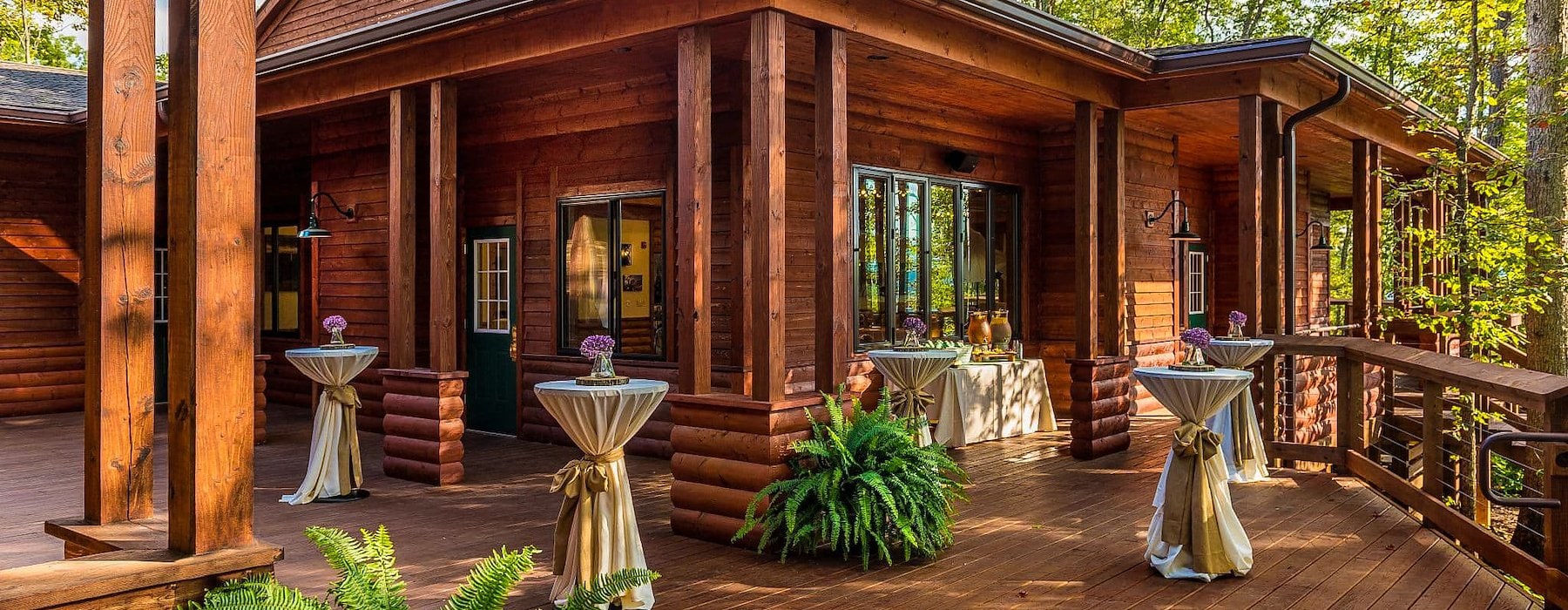 Wooden deck with a rustic cabin and tall windows surrounded by trees Adventures on the Gorge - Lansing West Virginia USA