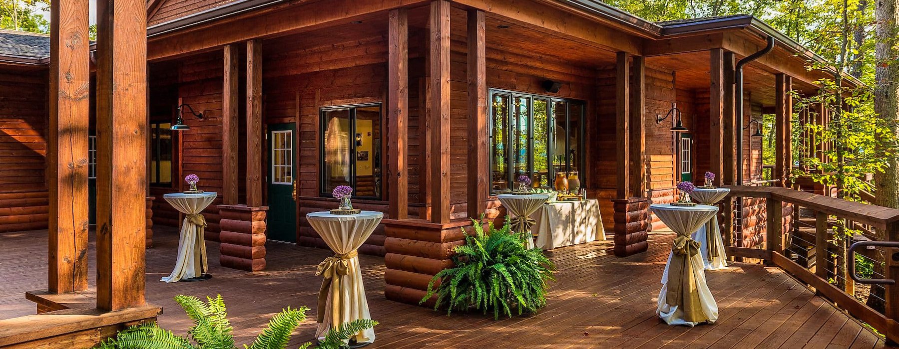 Wooden deck with a rustic cabin and tall windows surrounded by trees Adventures on the Gorge - Lansing West Virginia USA