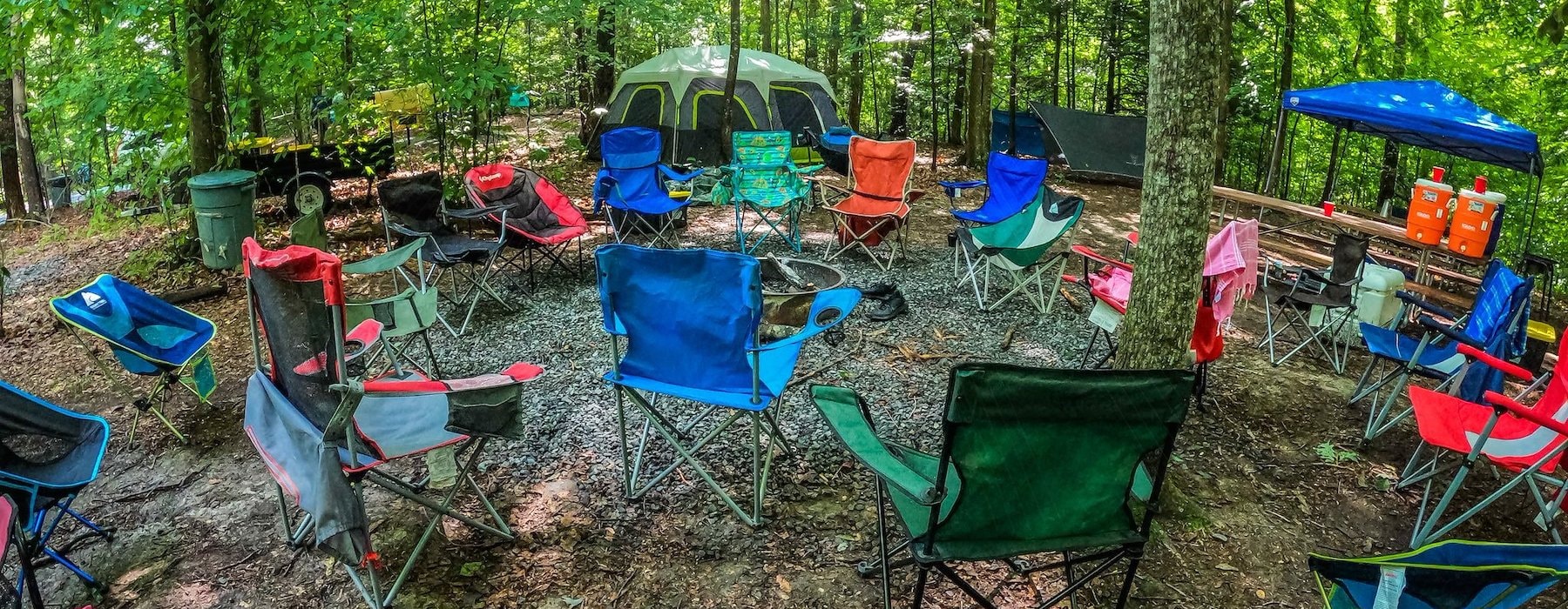 a campsite in the new river gorge with tents, chairs, and picnic tables