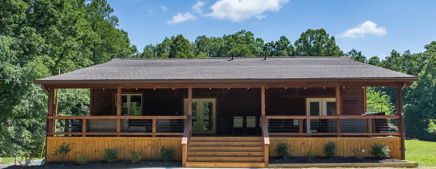 Rustic log cabin with porch, deck, trees