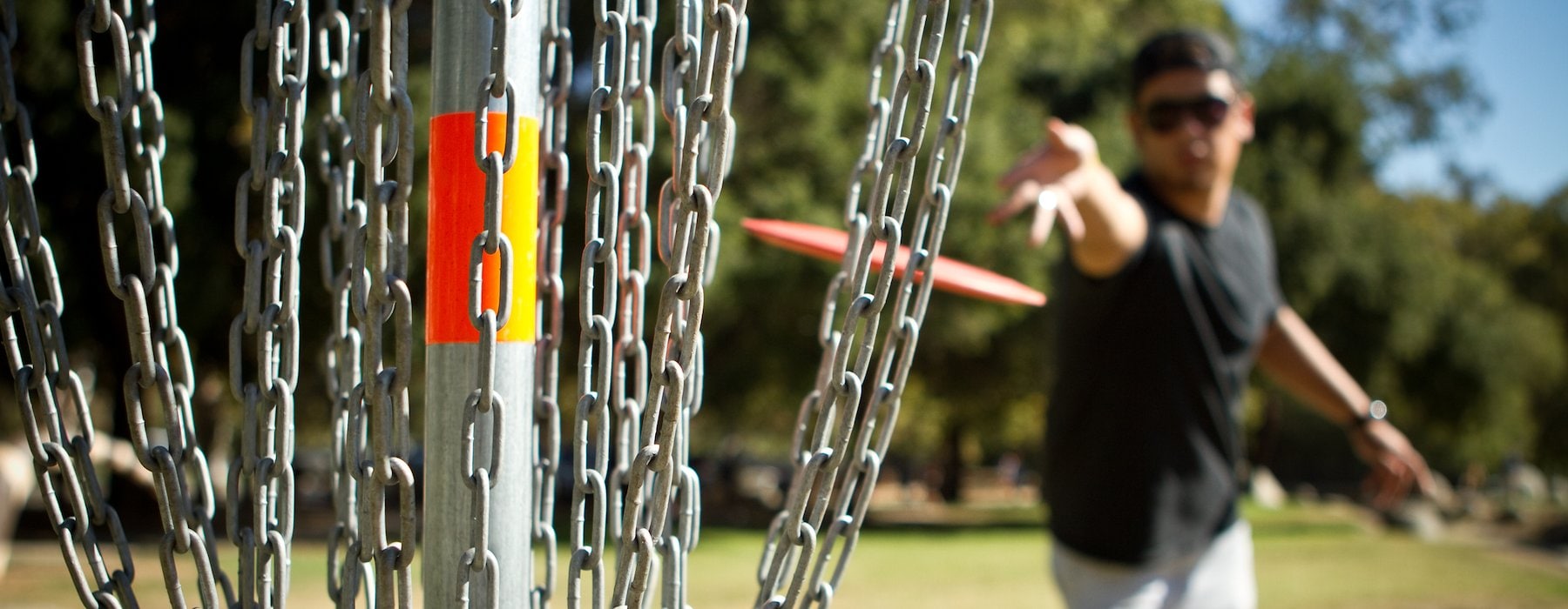 Adventures on the Gorge Lansing West Virginia USA - A person in a park throws an orange disc towards a metal disc golf basket
