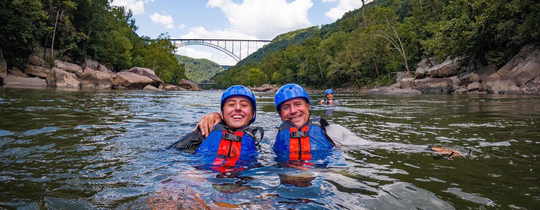 Two people smile while floating in a river Adventures on the Gorge - Lansing West Virginia USA
