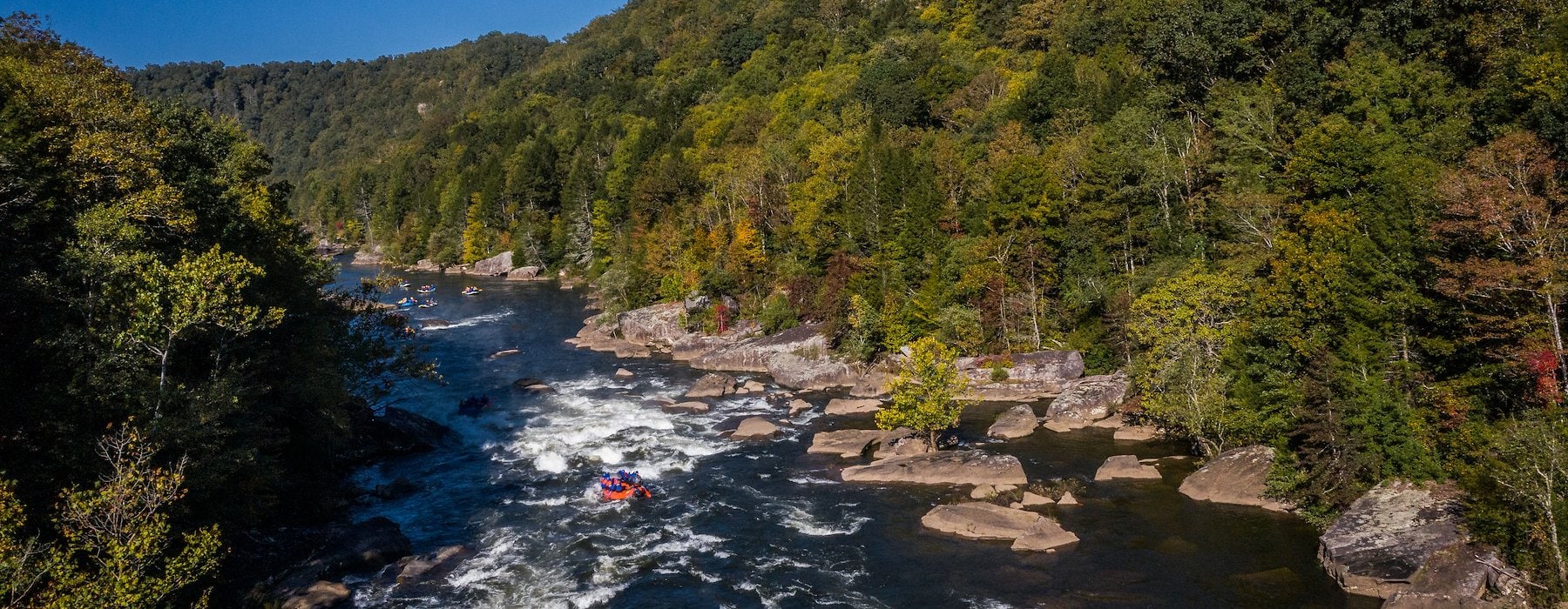A picturesque river with smooth rocks and a backdrop of trees Adventures on the Gorge - Lansing West Virginia USA