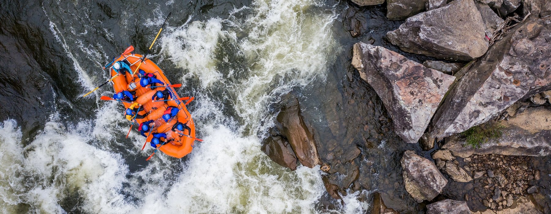 A team of people in an orange raft tackling a swift river Adventures on the Gorge - Lansing West Virginia USA