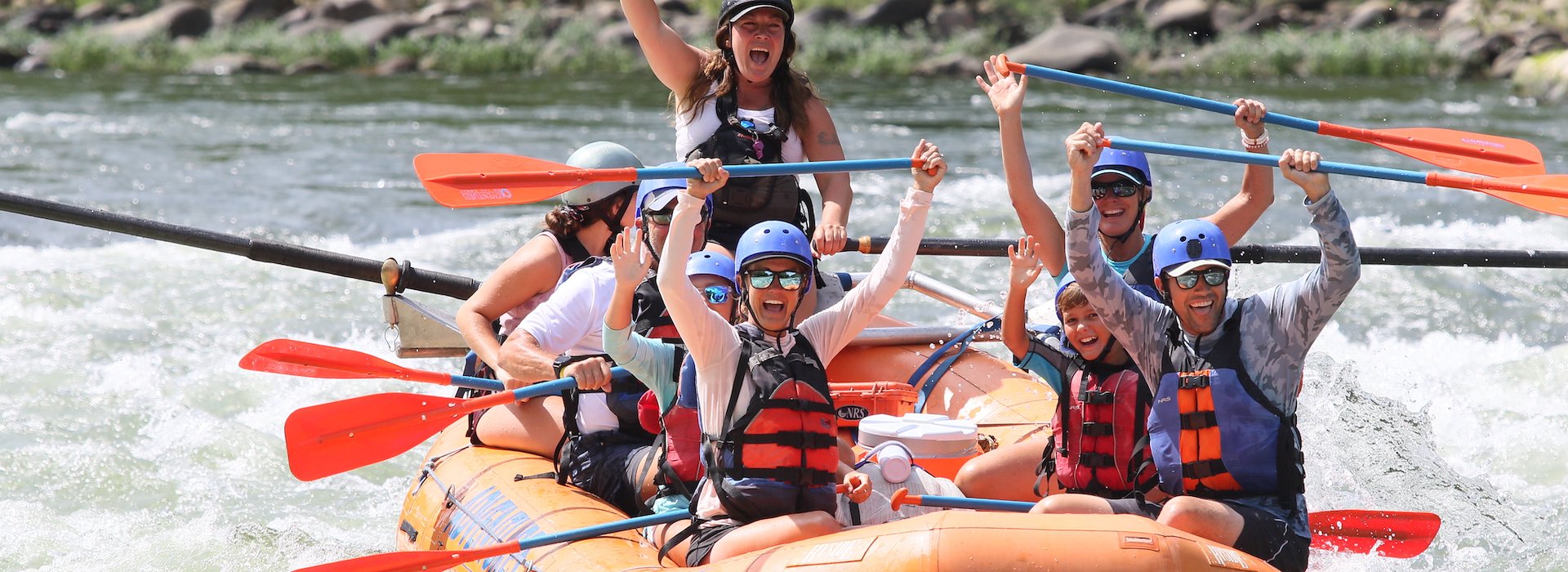 life jackets are joyfully rafting down a choppy river in an orange inflatable boat Adventures on the Gorge - Lansing West Virginia USA