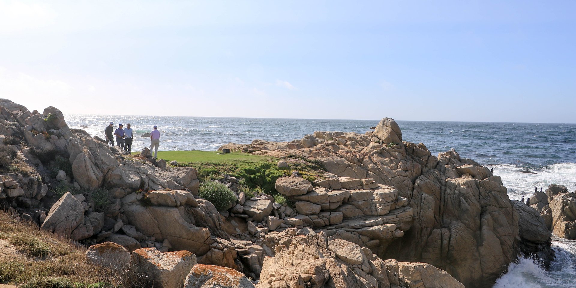 A group of people stand on rocky cliffs overlooking Asilomar Hotel and Conference Grounds - Pacific Grove California