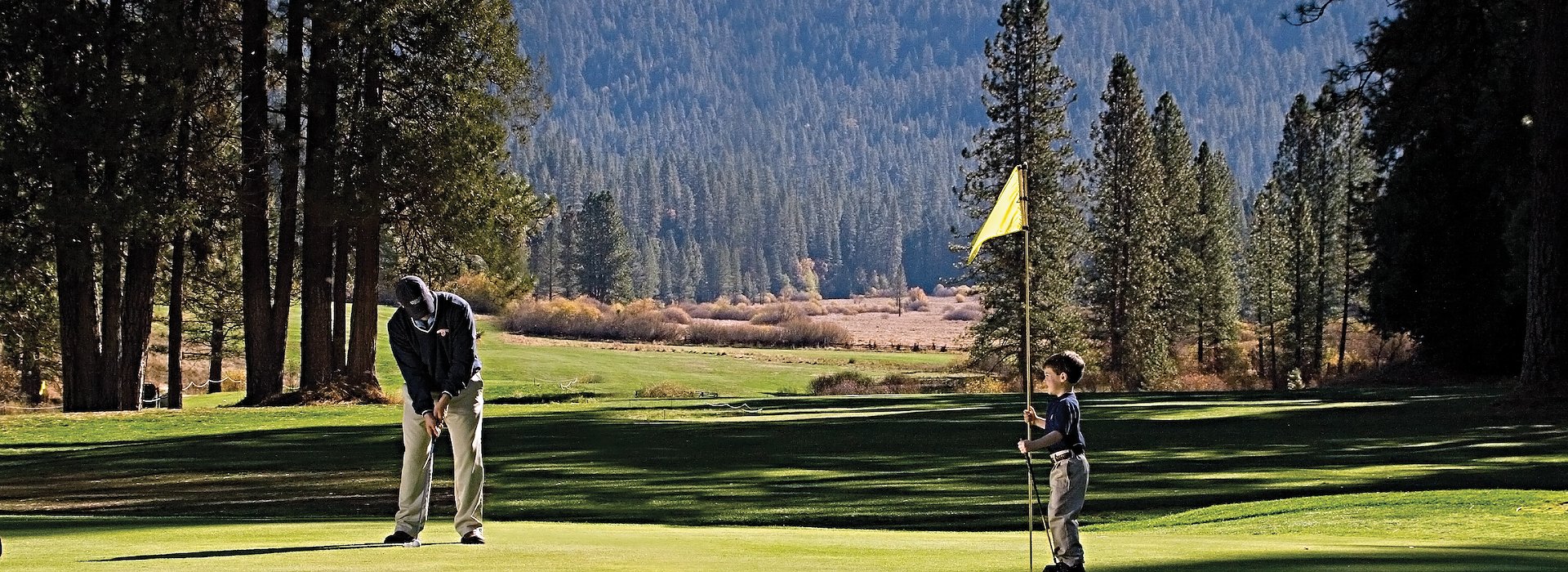 Golf playing and a child holds the flagstick Yosemite National Park Lodging and Activities - California - United States