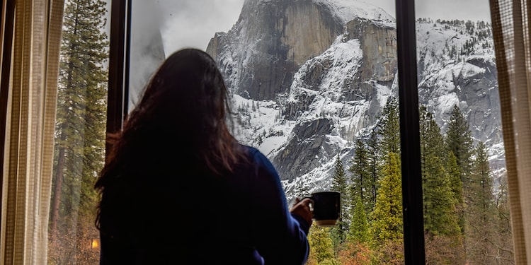 A woman holding a cup looking out a window