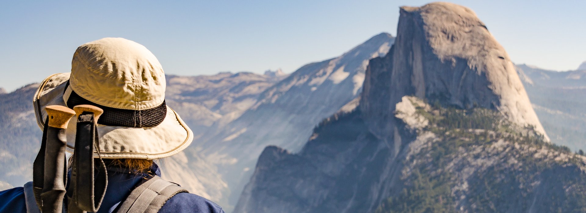 Yosemite National Park Lodging and Activities California United States - A hiker wearing a sun hat and backpack with trekking poles